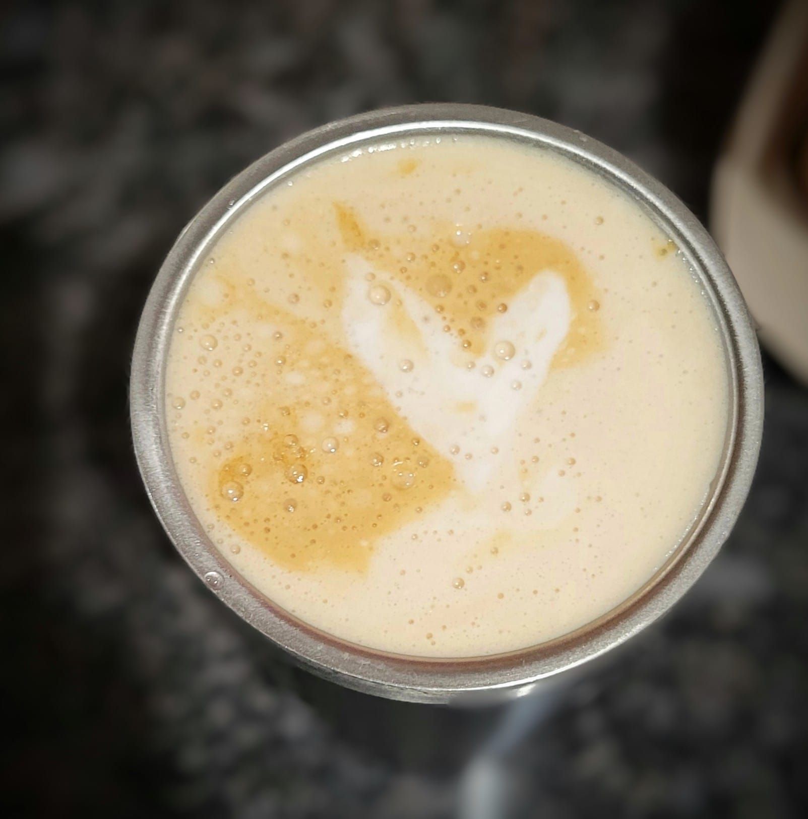 A close up of a glass of beer with a heart in the foam