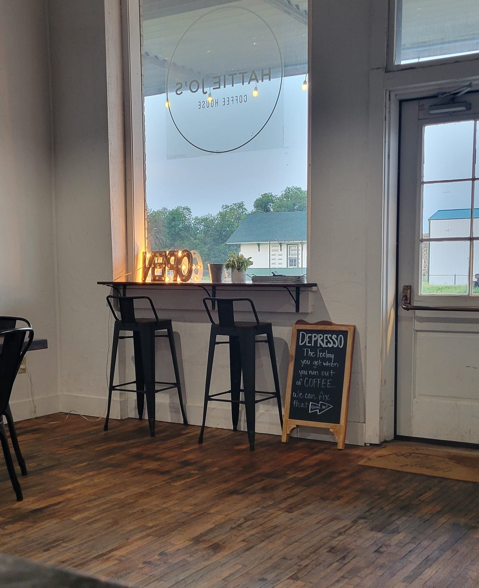 A room with a table and stools in front of a window.