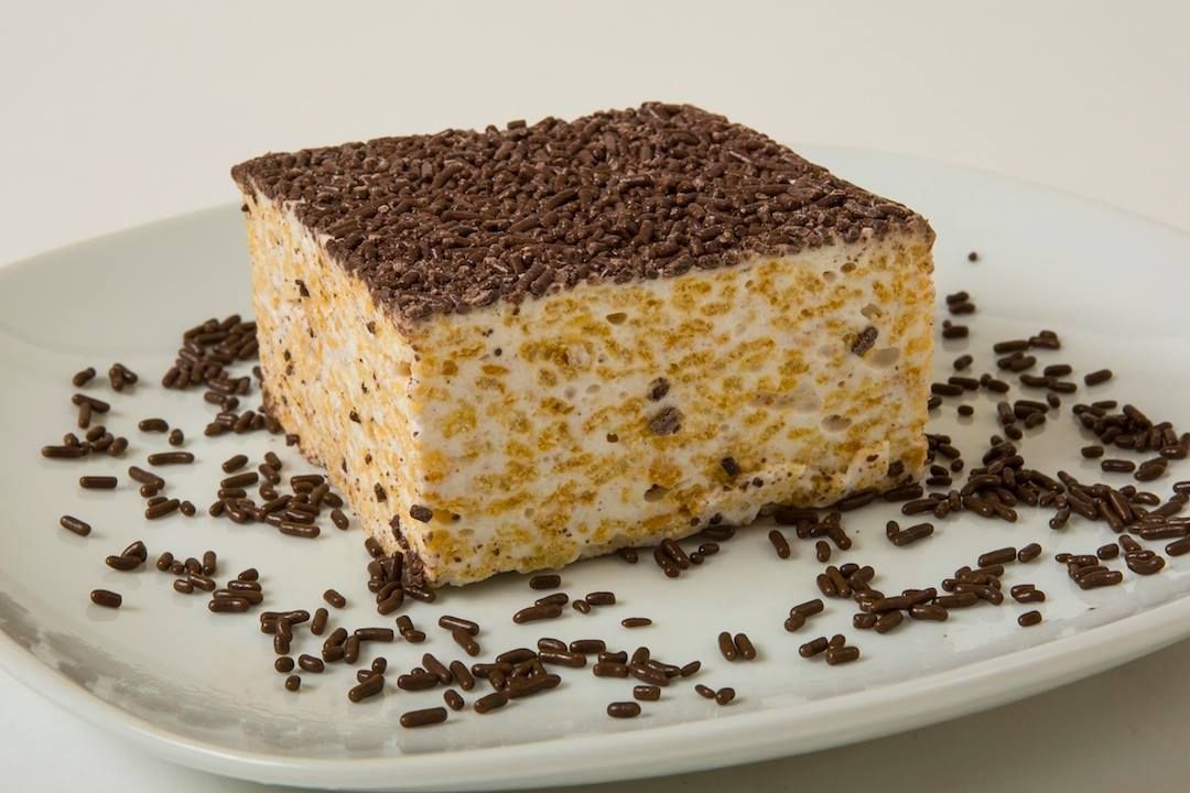 A piece of cake with chocolate sprinkles on a white plate.