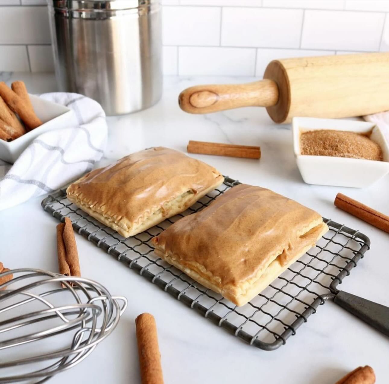 Two pastries are sitting on a cooling rack next to a rolling pin