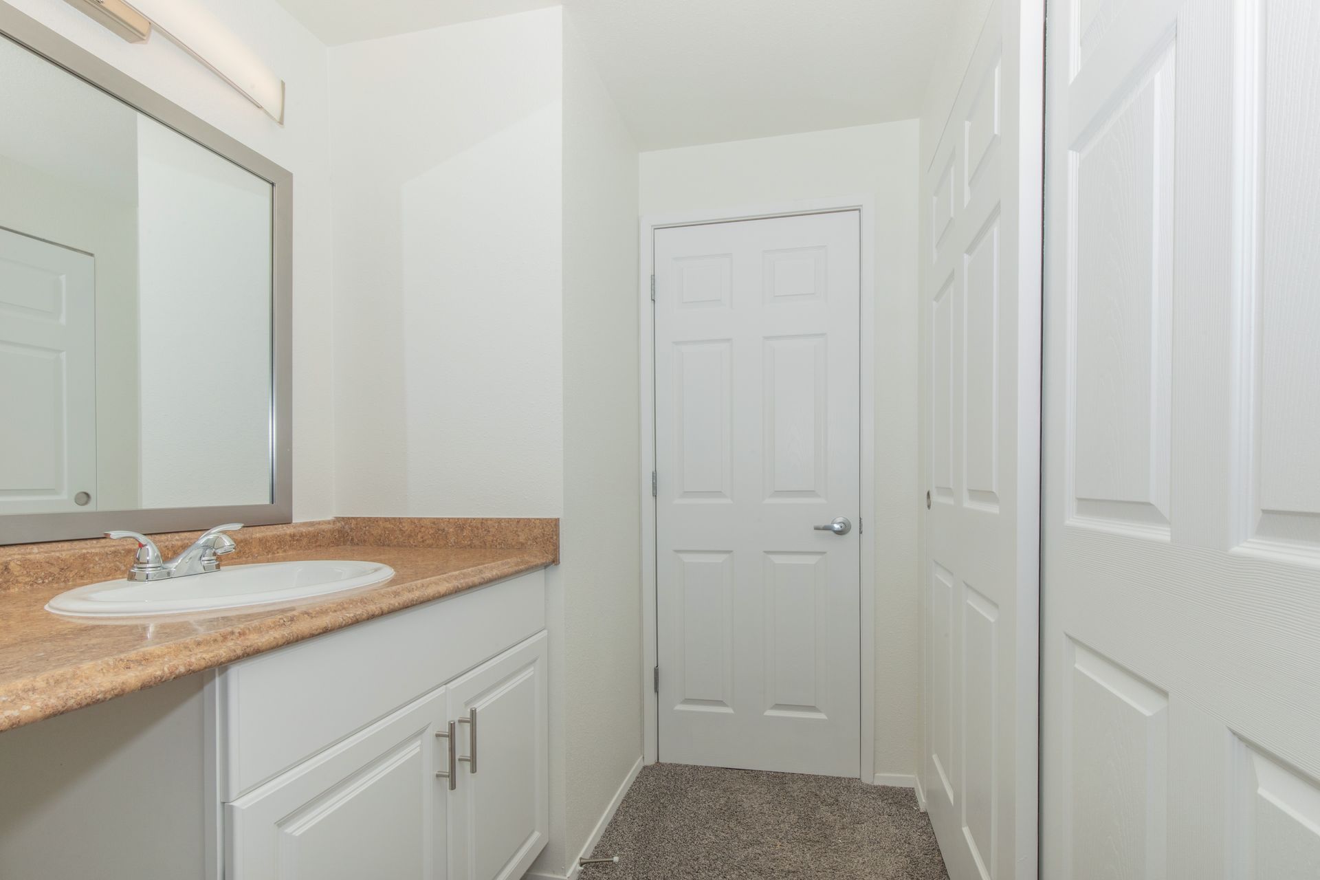 A bathroom with a sink , mirror and closet.