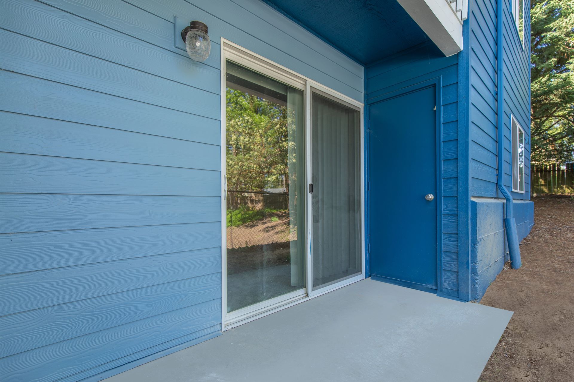 A blue house with a patio and a sliding glass door.