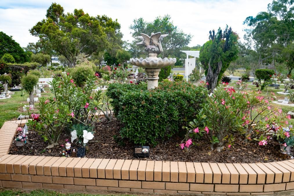 A Brick-Bordered Flower Bed with A Fountain in A Cemetery; Green Bushes Surround the Fountain — Rockhampton Crematorium in Norman Gardens, QLD