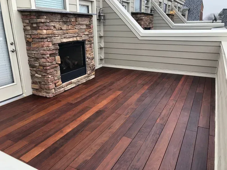 Beige townhouse with large windows and a wooden deck, overcast sky.