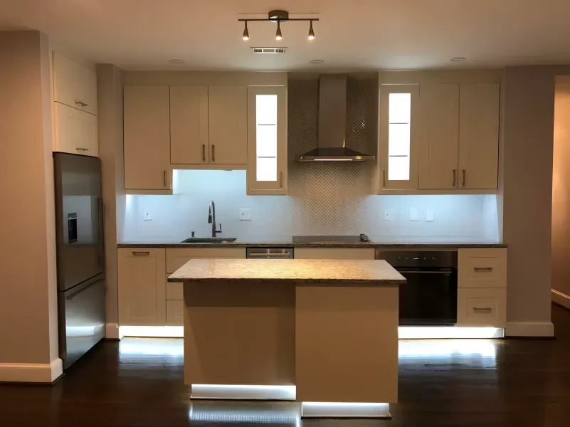 Modern kitchen with white cabinets, island, and stainless steel appliances.