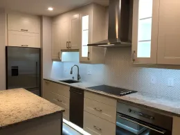 Modern kitchen with white cabinets, stainless steel appliances, granite countertops, and a small island.