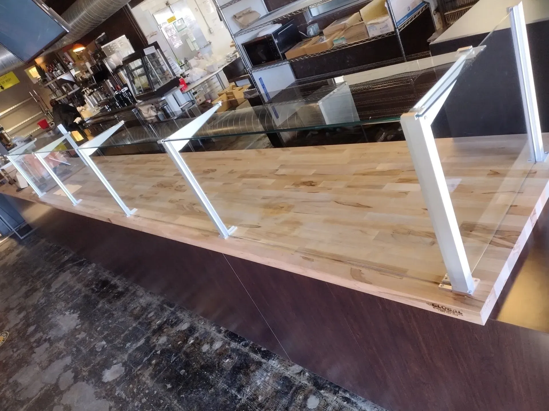 A wooden table with a glass sneeze guard in a restaurant.