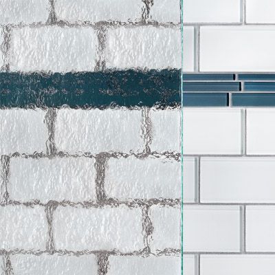 A close up of a brick wall with white tiles and a blue tile border with patterned glass on top.