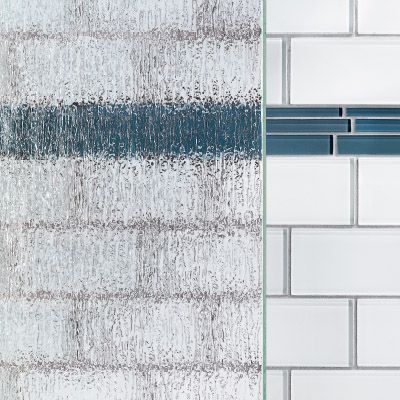 A close up of a textured glass piece and a white brick wall with blue tiles.