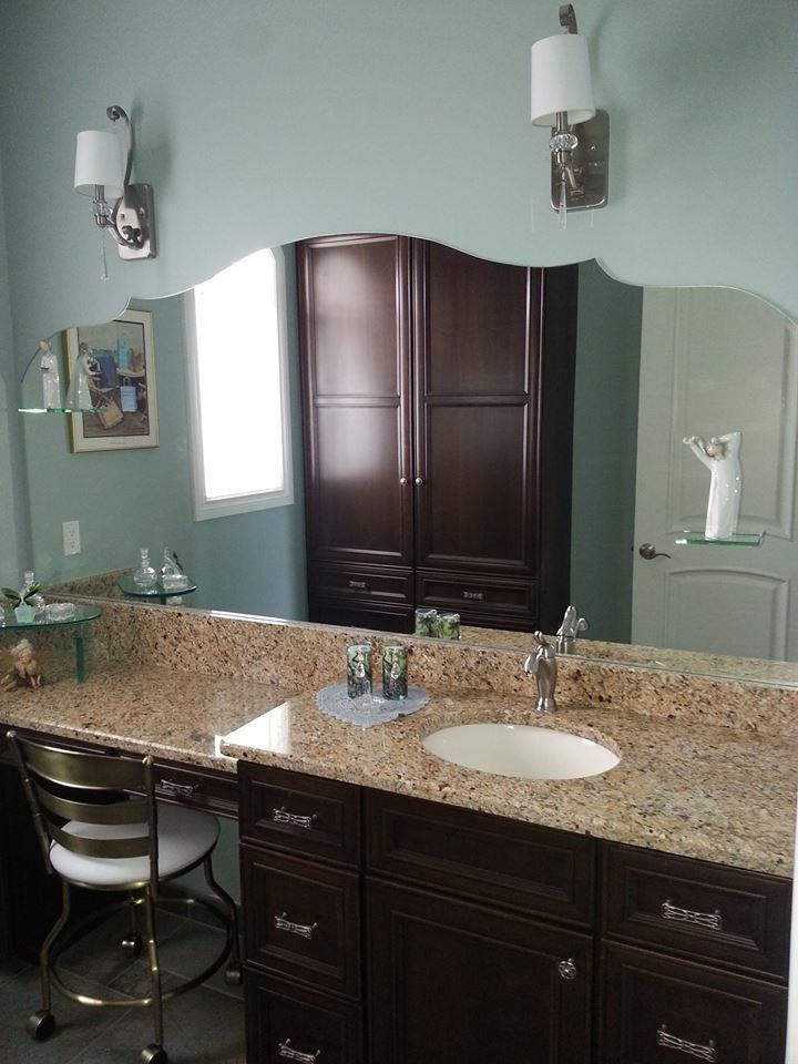 Bathroom with brown vanity, granite countertop, oval sink, and large mirror.