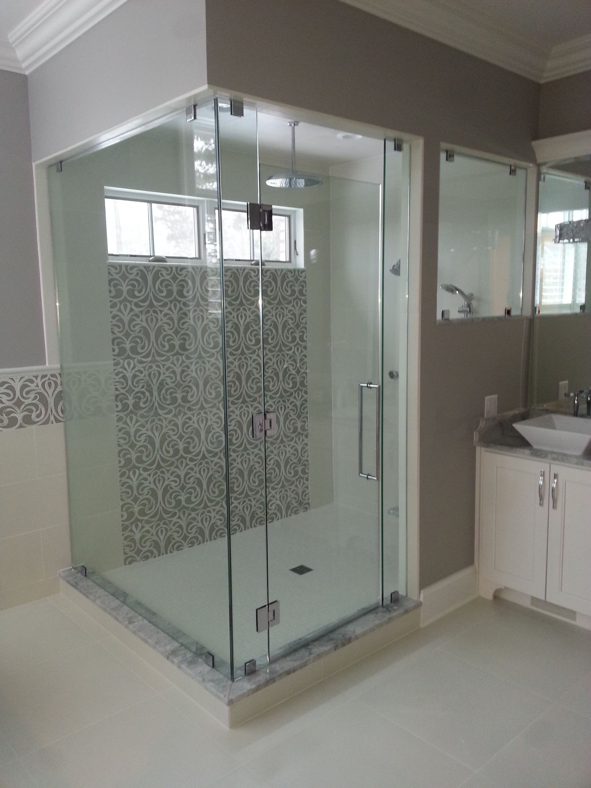 Glass shower enclosure with mosaic tile accents in a modern bathroom.