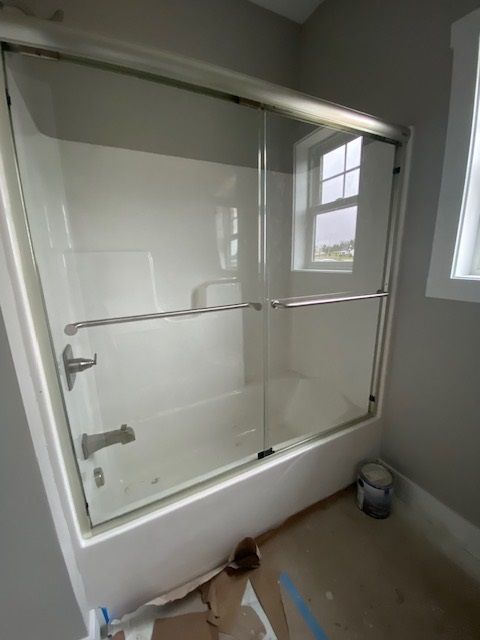 White bathroom tub with sliding glass doors.