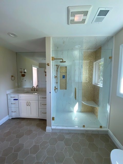 Bathroom with large glass shower, vanity, and hexagonal tile flooring.