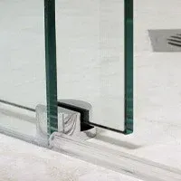 A close up of a glass shower door in a bathroom with slide bottom.