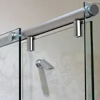 A close up of a sliding glass shower door in a bathroom showing hinges.