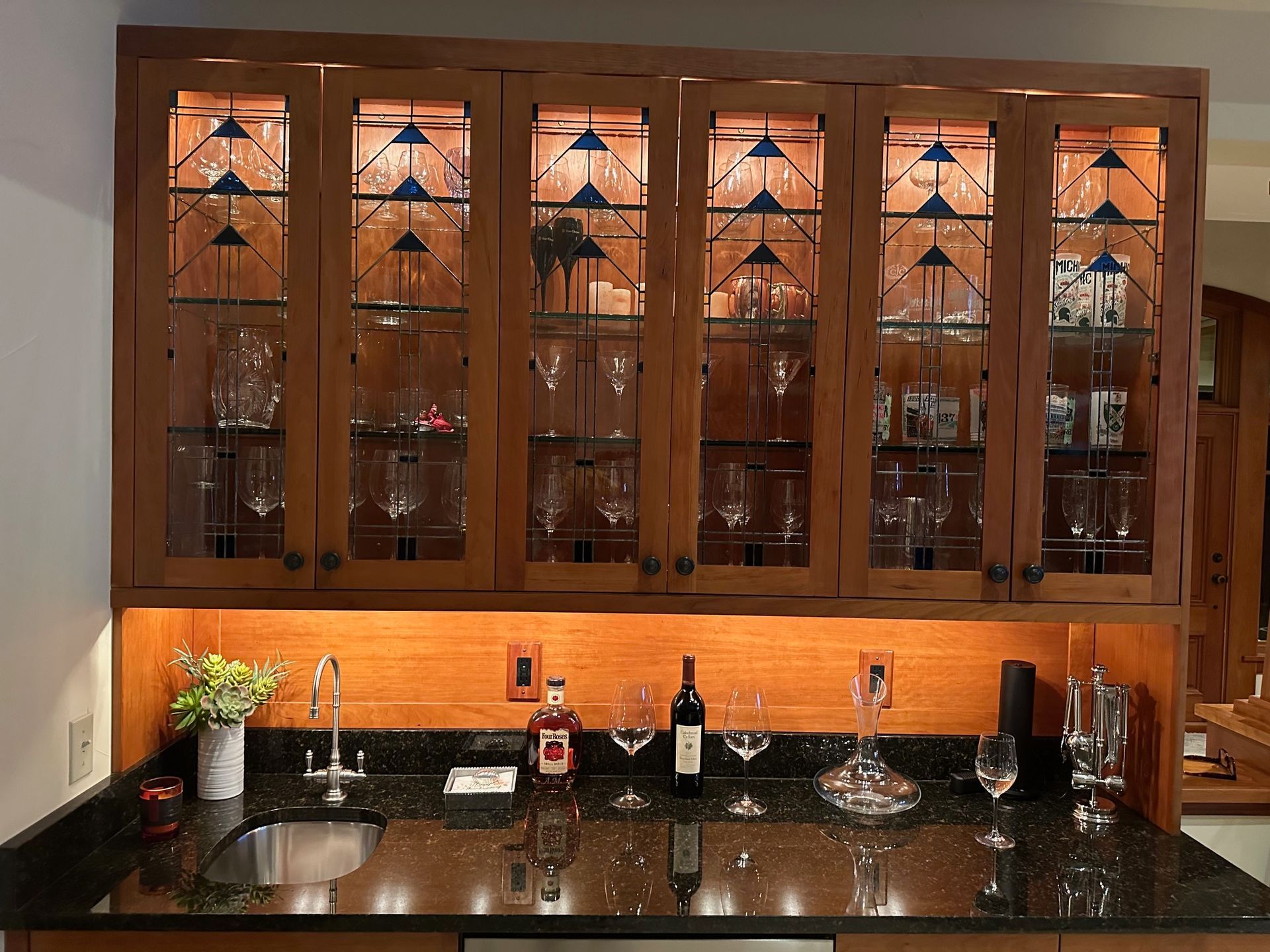 A kitchen with a bottle of wine on the counter and cabinets with glass fronts.