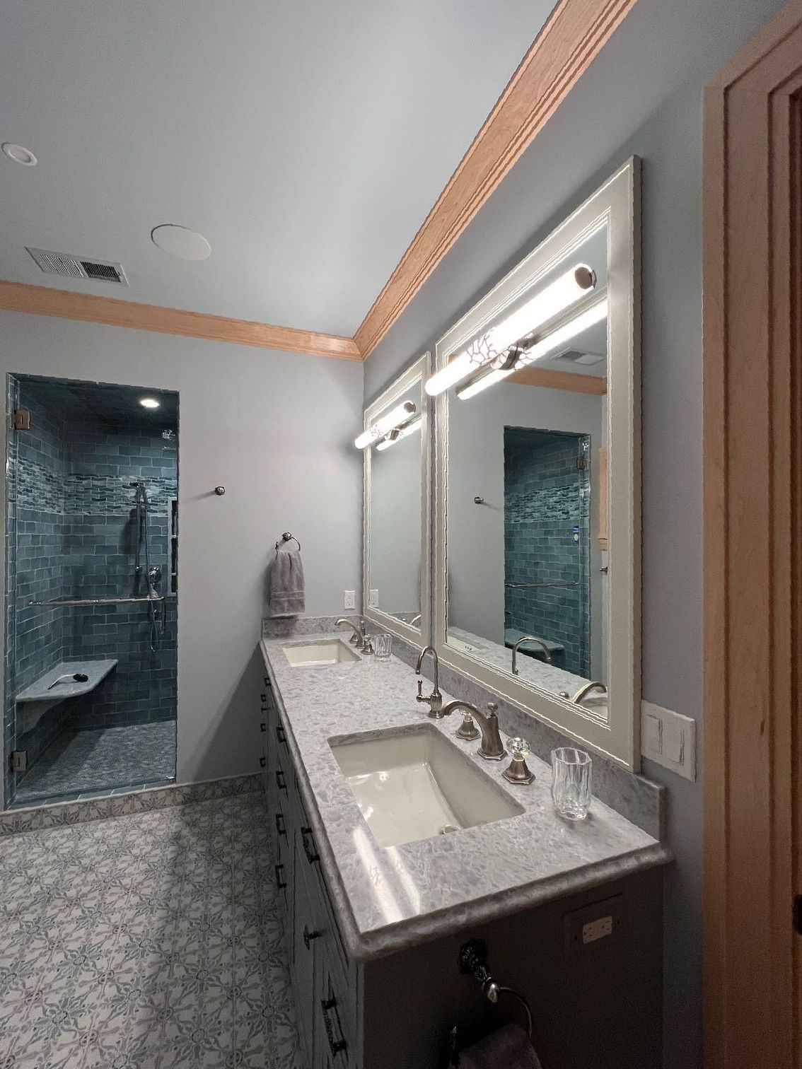 A bathroom with two sinks , two mirrors and a walk in shower.