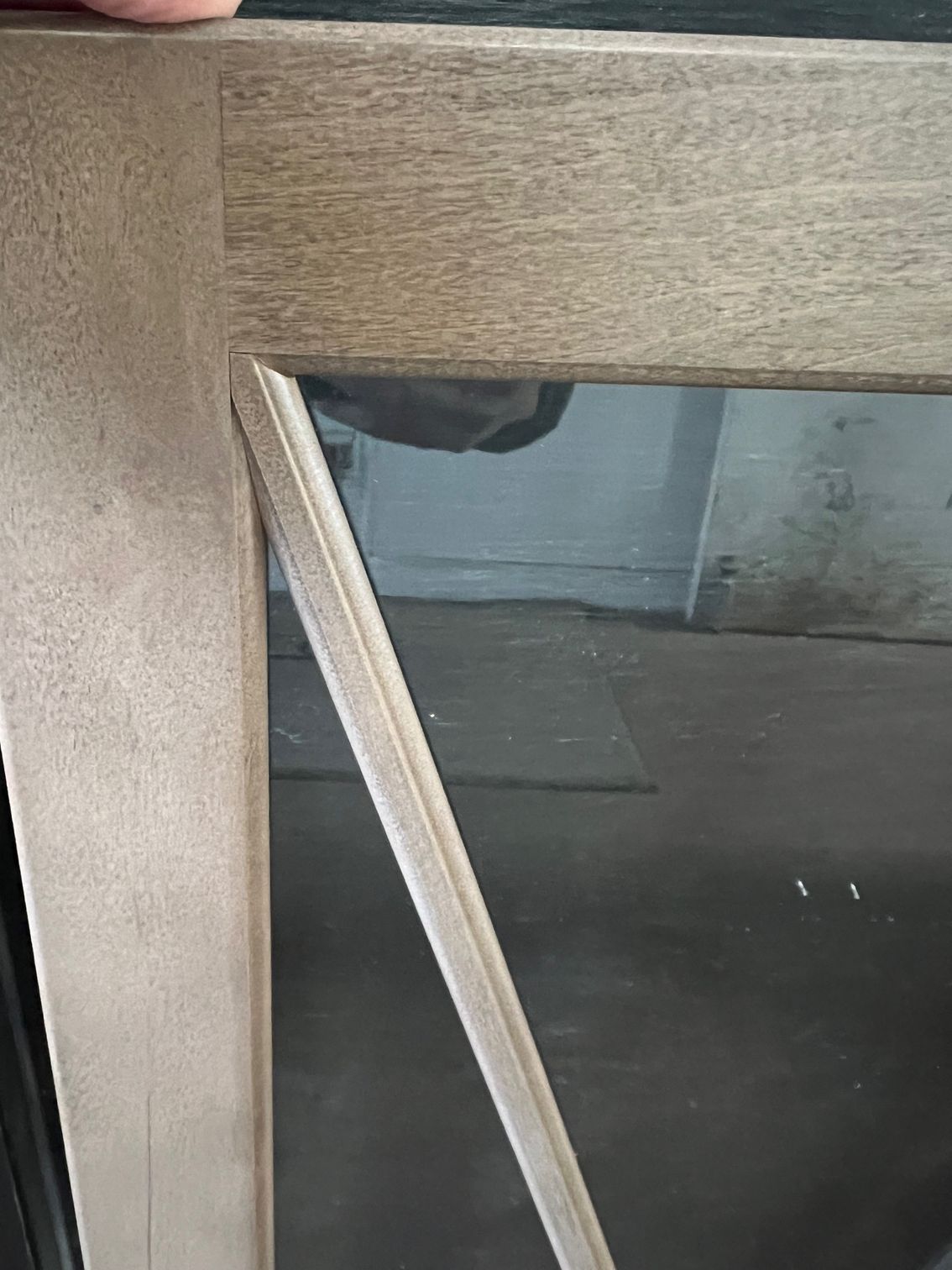 A person is holding a piece of wood next to a window.