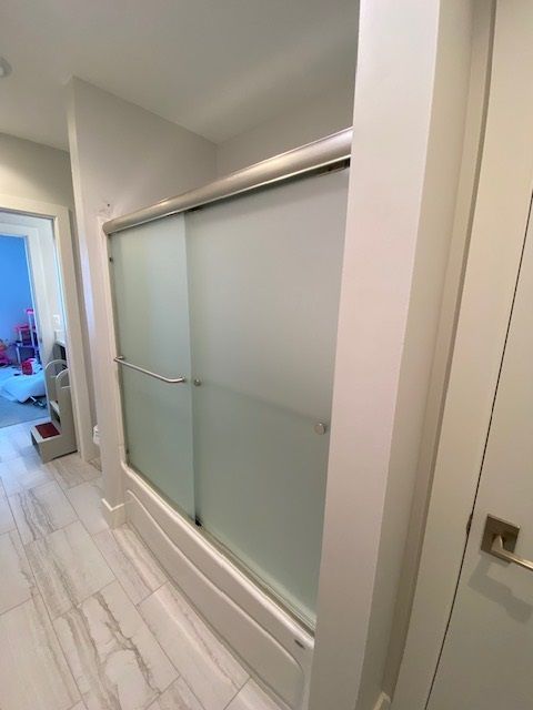 Frosted glass shower enclosure in a bathroom with white trim and tiled floor.