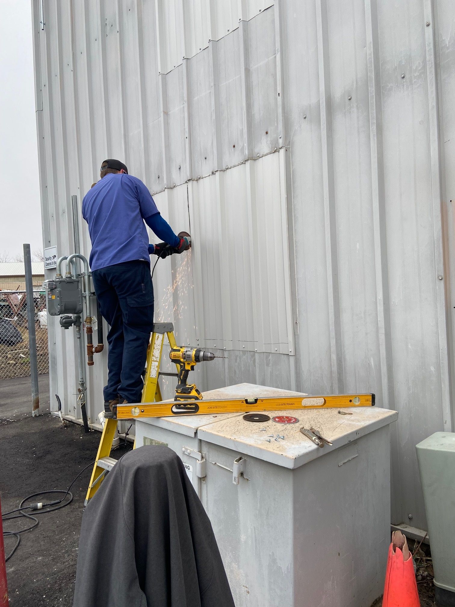 A man is standing on a ladder working on a wall.