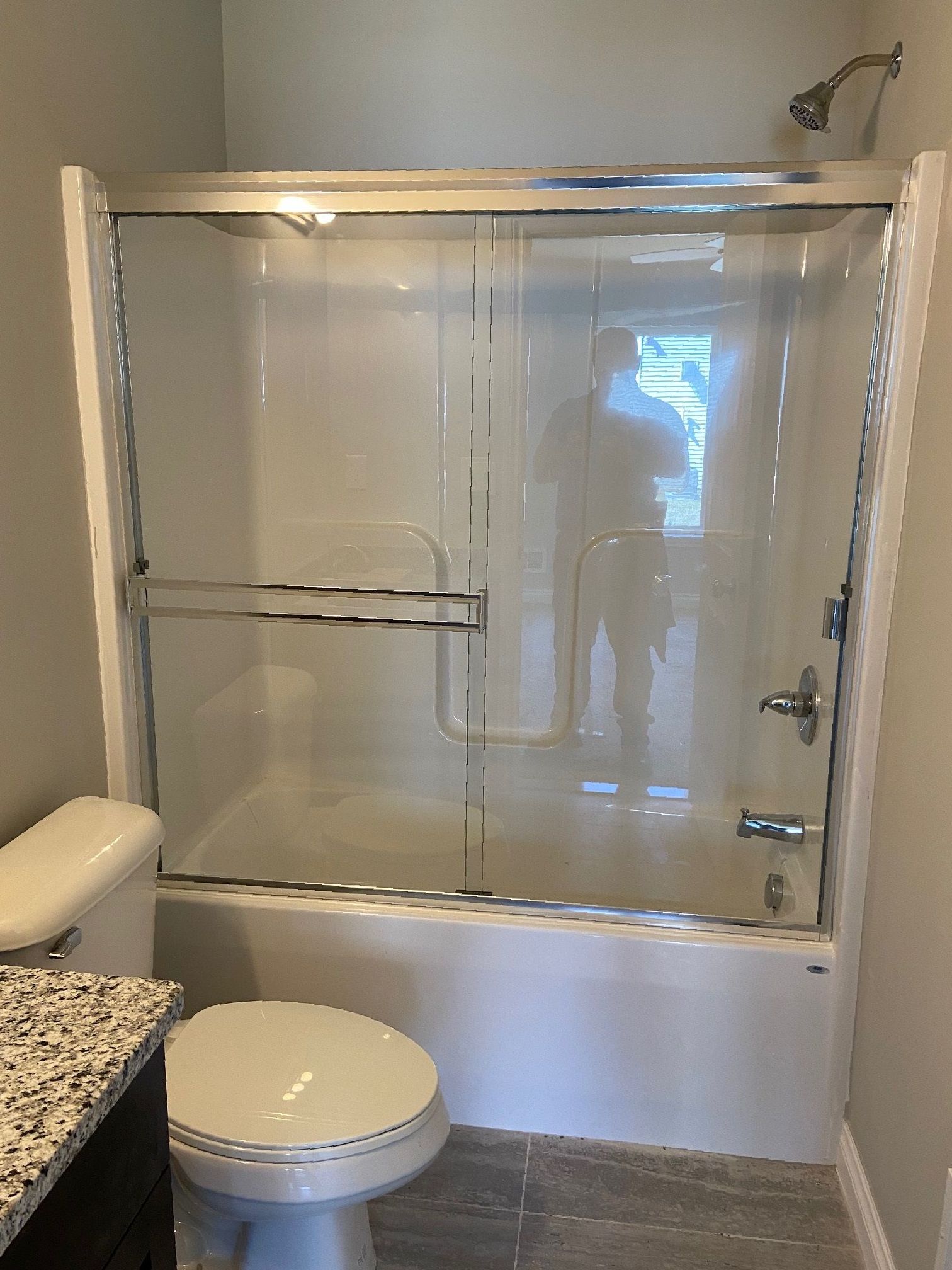 A bathroom with a toilet , tub and shower with glass doors.