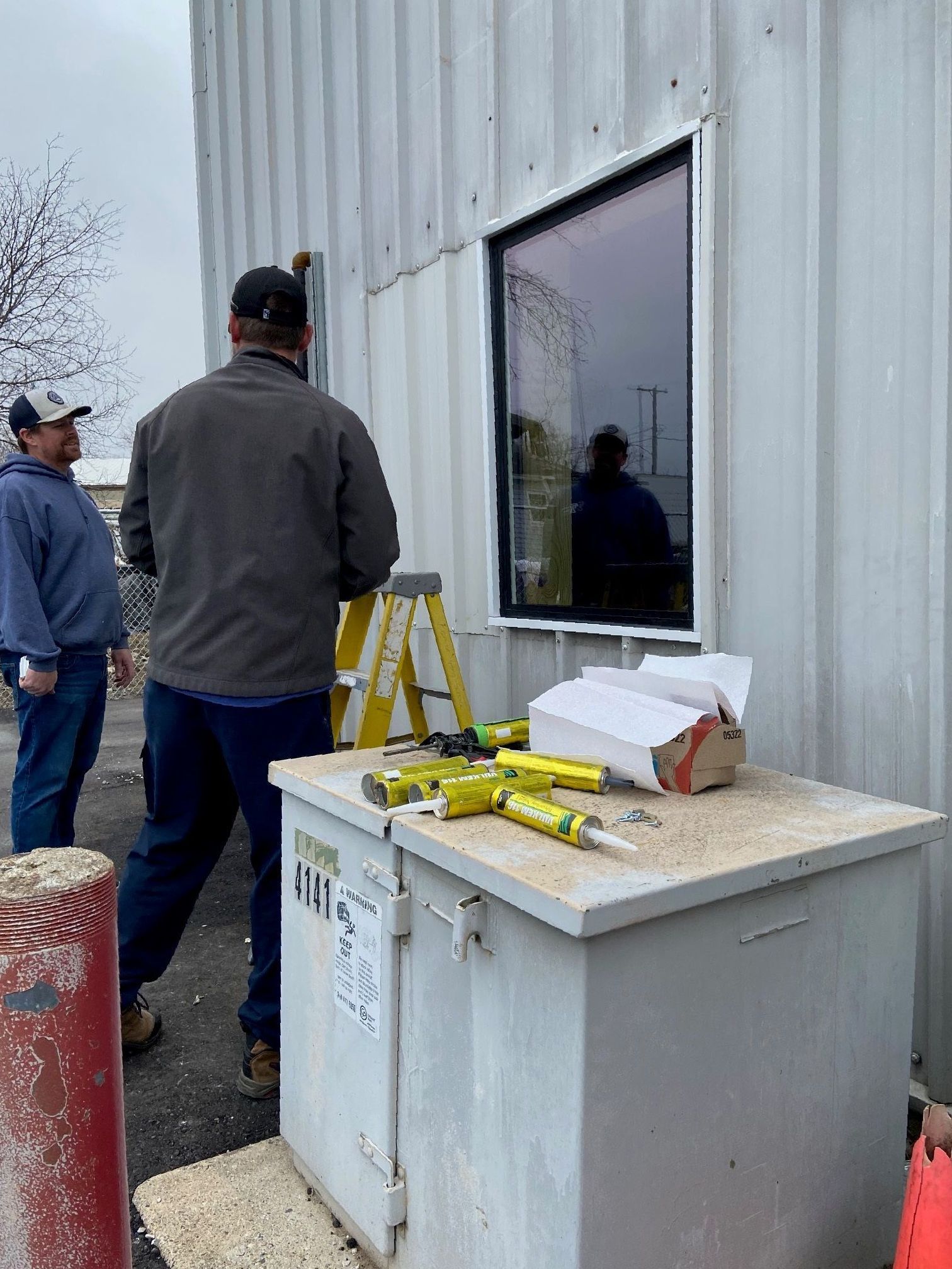 A man is standing in front of a building looking at a window.