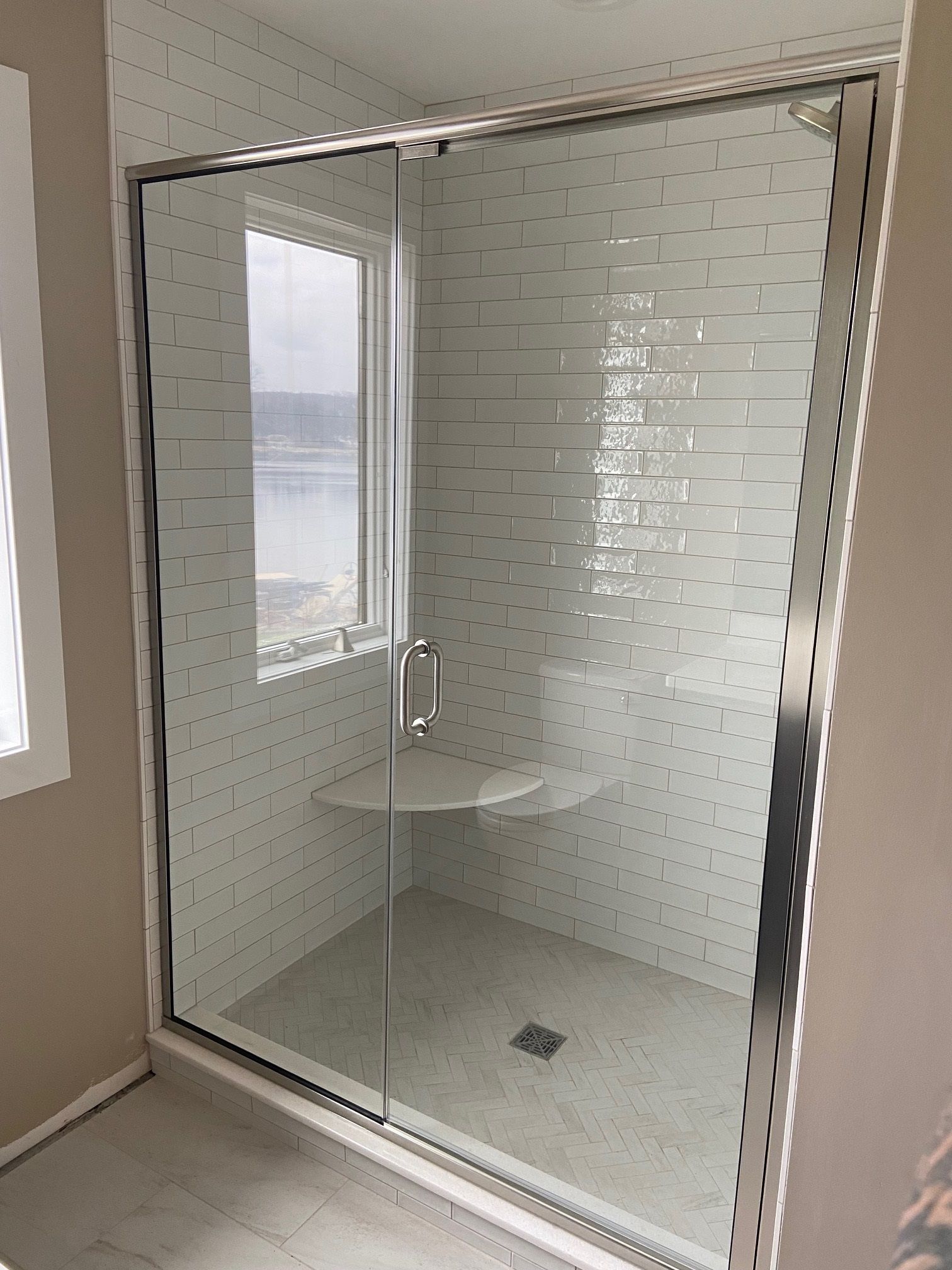 A bathroom with a sliding glass shower door and a window.