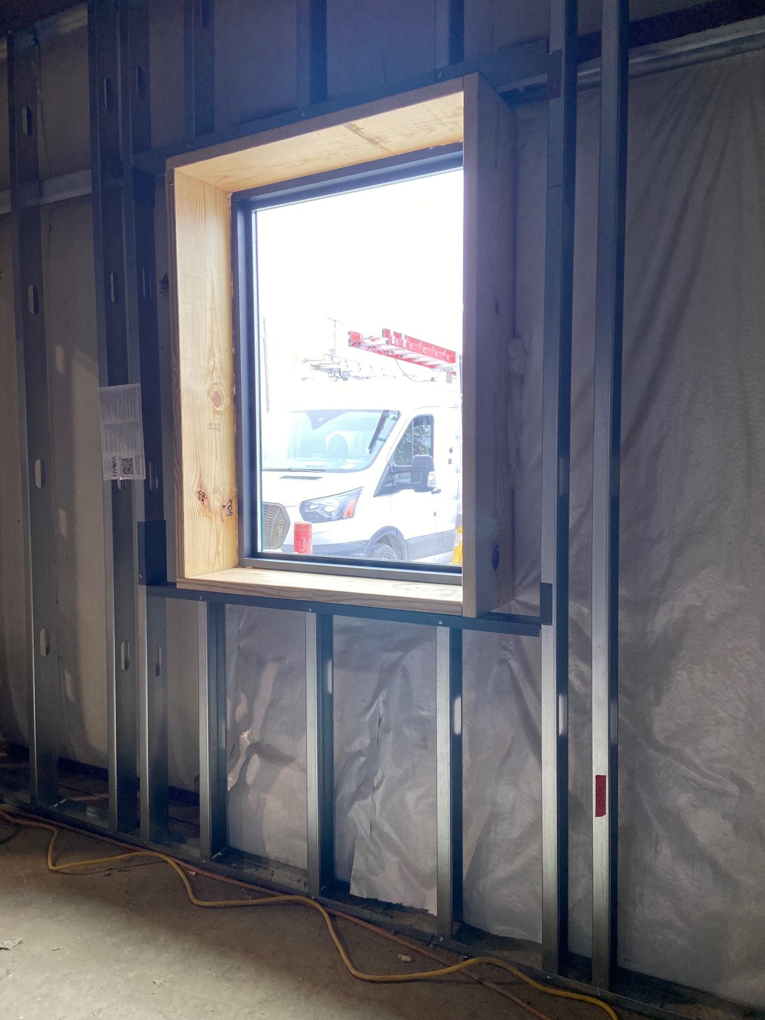 There is a window in the wall of a building under construction.