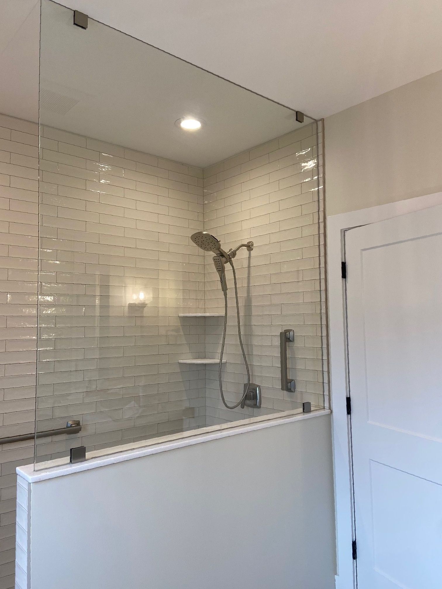 A bathroom with a walk in shower with a glass door and a shower head.