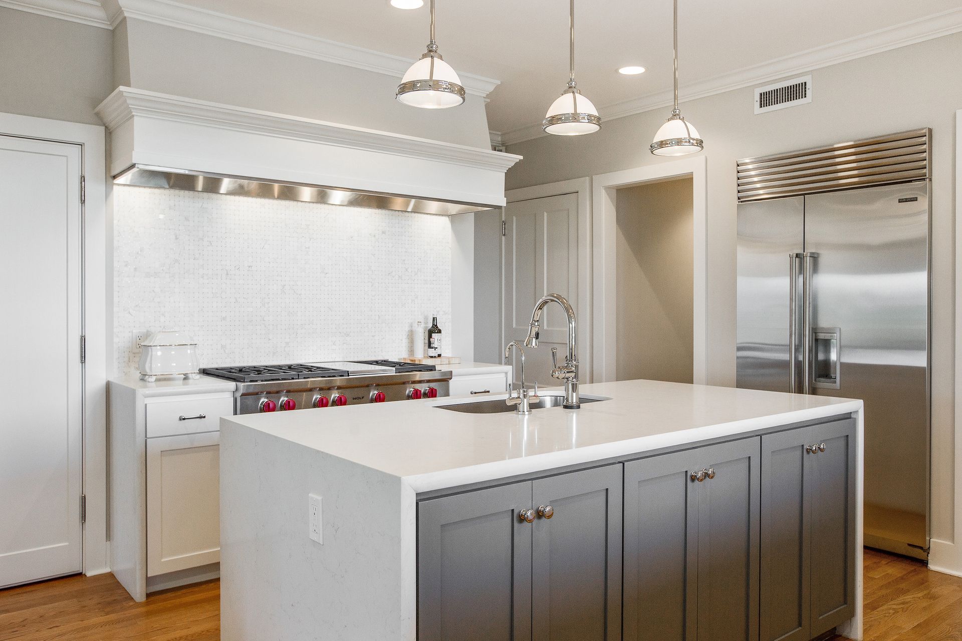 A kitchen with white cabinets and a large island in the middle.