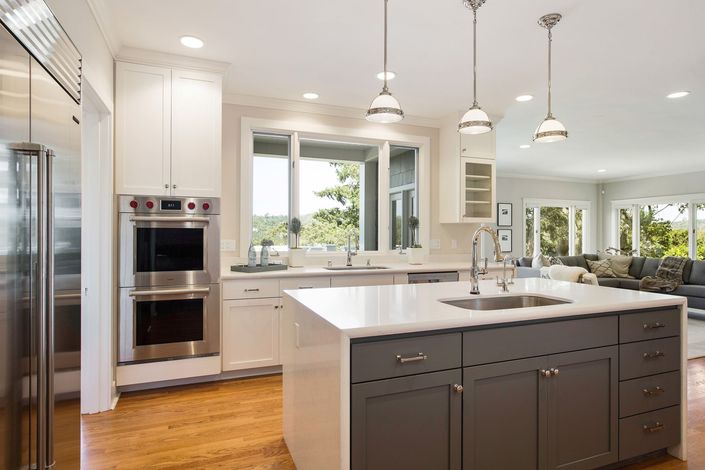 A kitchen with white cabinets and a large island in the middle.