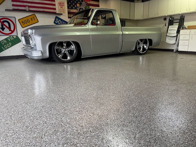 A silver truck is parked in a garage with signs on the wall