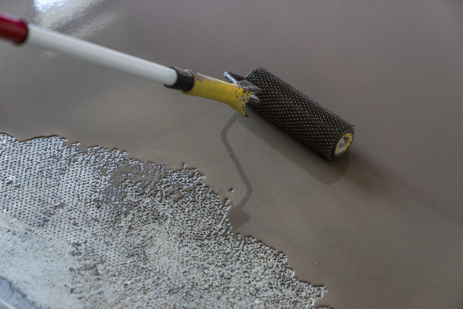 A person is painting a floor with a roller.