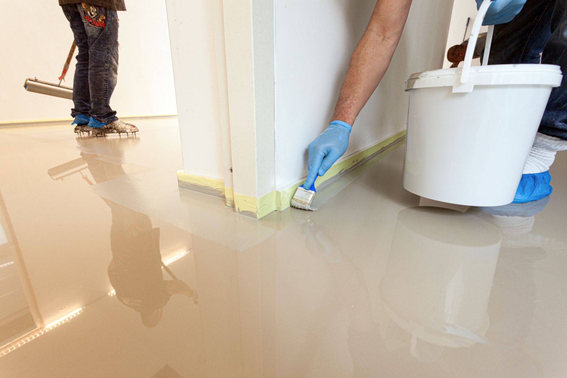 A person is painting a floor with a brush.