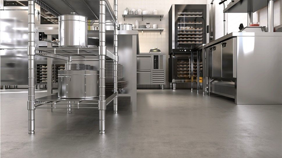 A kitchen with stainless steel appliances and a concrete floor.