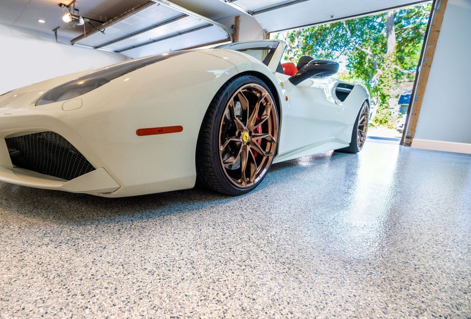 A white sports car is parked in a garage.