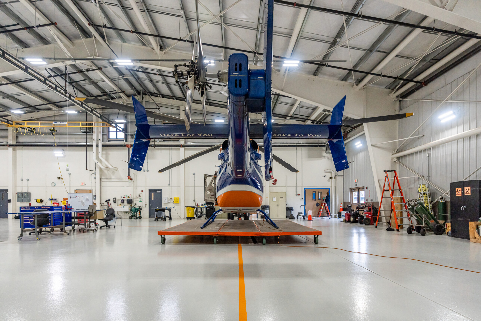 a blue and orange helicopter is parked in a hangar .