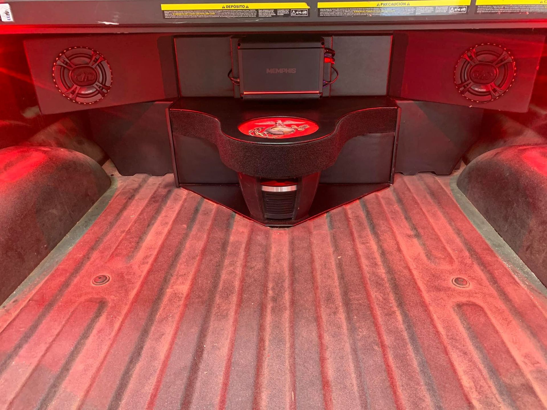 A truck bed modified with a custom audio system, including speakers, an amplifier, and a subwoofer.