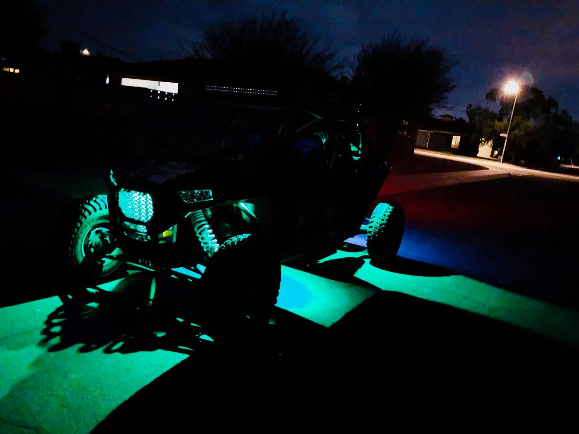 A modified off-road vehicle glows with green under-glow lights at night.
