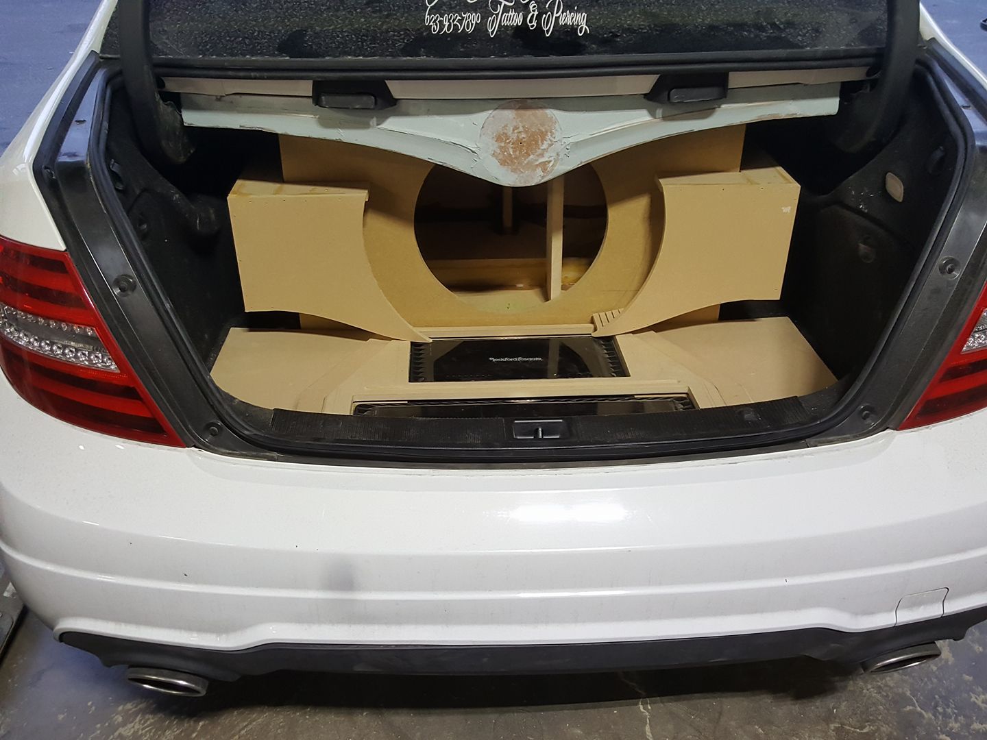 A white car trunk with cardboard cutouts for car audio installation.