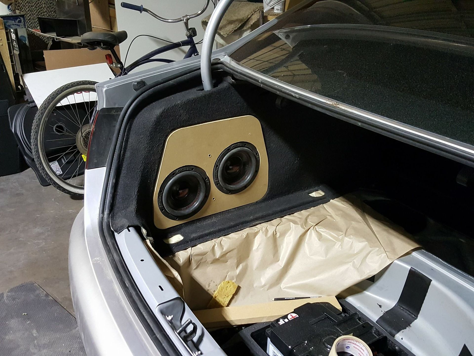 Car trunk with a custom speaker box featuring two speakers. The box is tan, and the trunk is open.