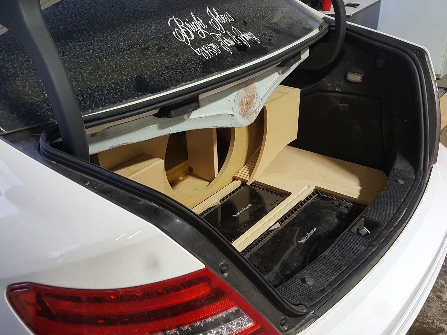 A car trunk with custom-built speaker boxes and amplifiers, possibly for an audio system upgrade.
