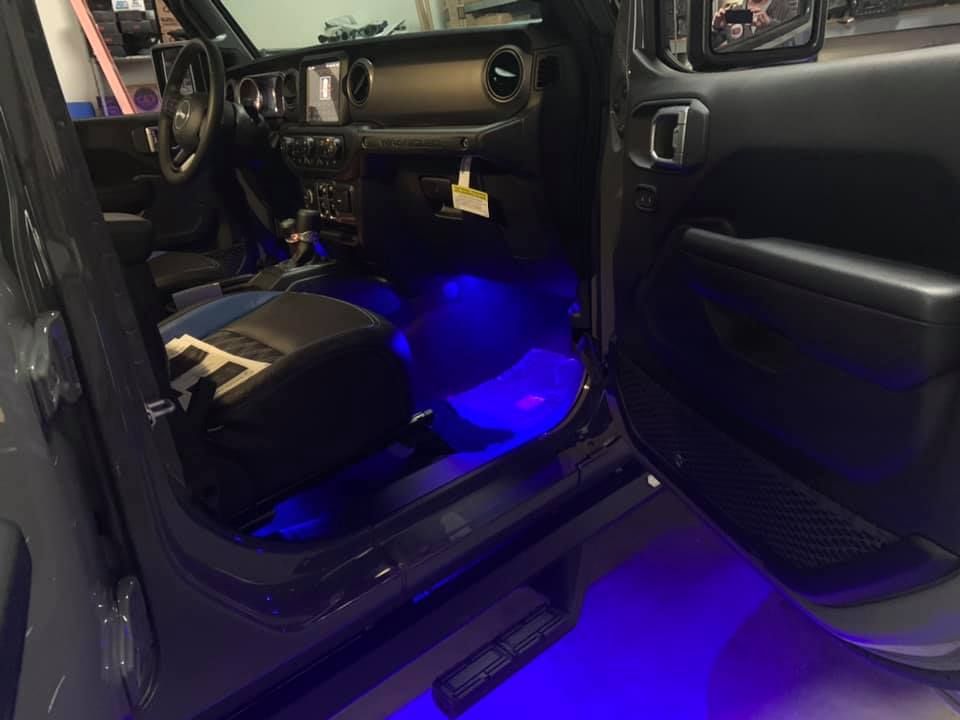 Interior of a gray Jeep with blue under-glow lighting.