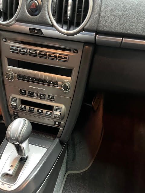 Interior view of a Porsche car dashboard. Silver-colored stereo system with a gear shift lever.