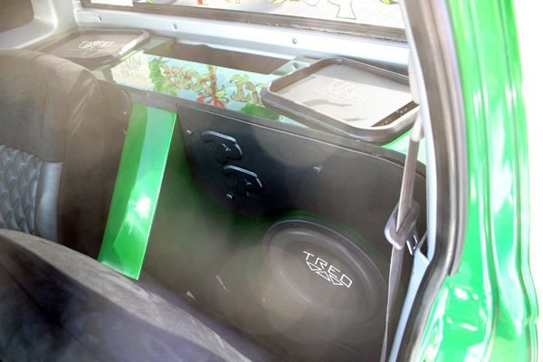 Green car interior featuring a custom subwoofer box with speakers and a green stripe.