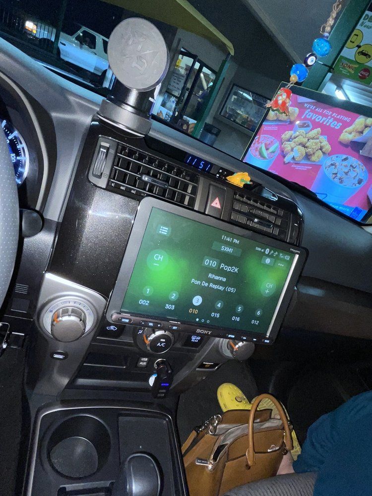 Interior view of a car with a large infotainment screen displaying a green interface.