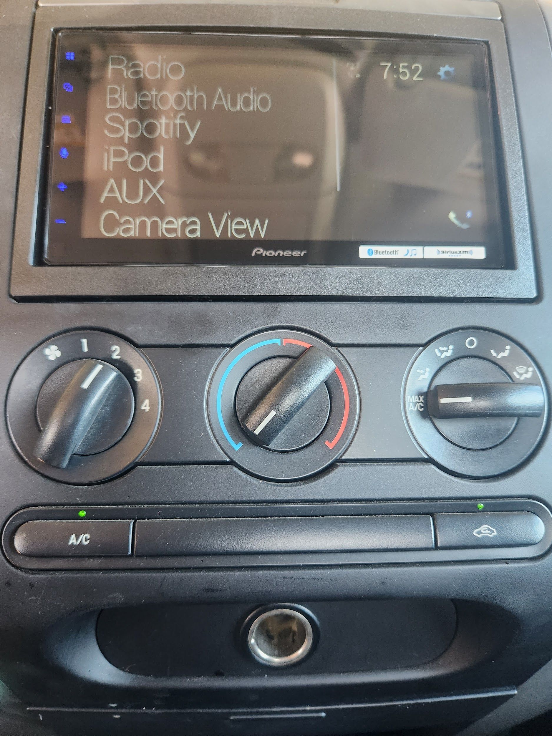 Car dashboard featuring a Pioneer touchscreen, climate control knobs, and a cigarette lighter.