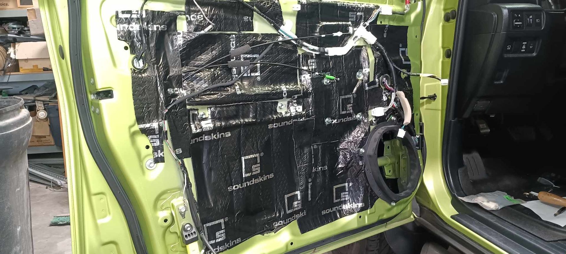 Inside view of a car door panel with sound dampening material installed. The door is lime green.