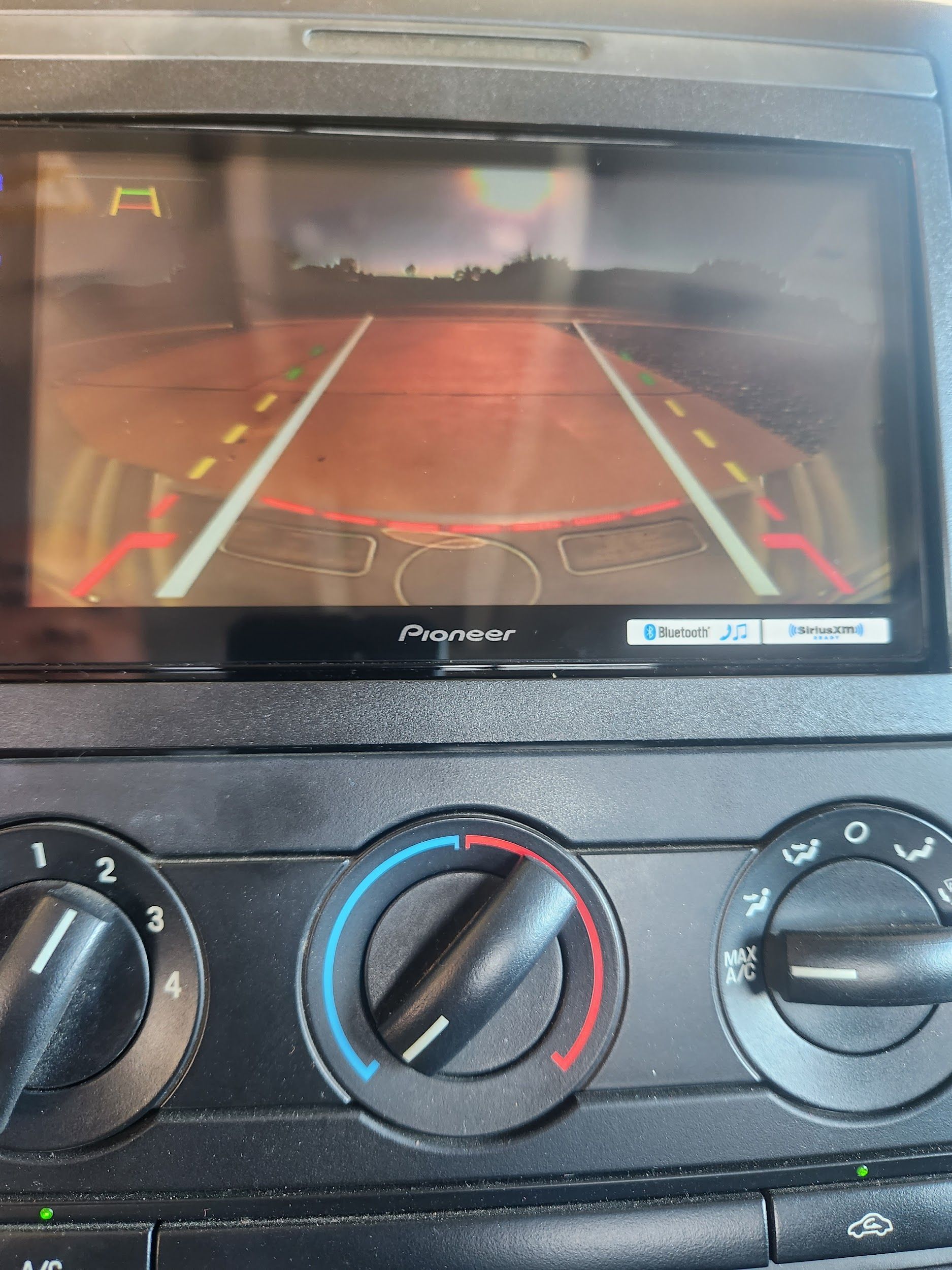 Backup camera display in a car, showing the view behind the vehicle with guiding lines on the screen.