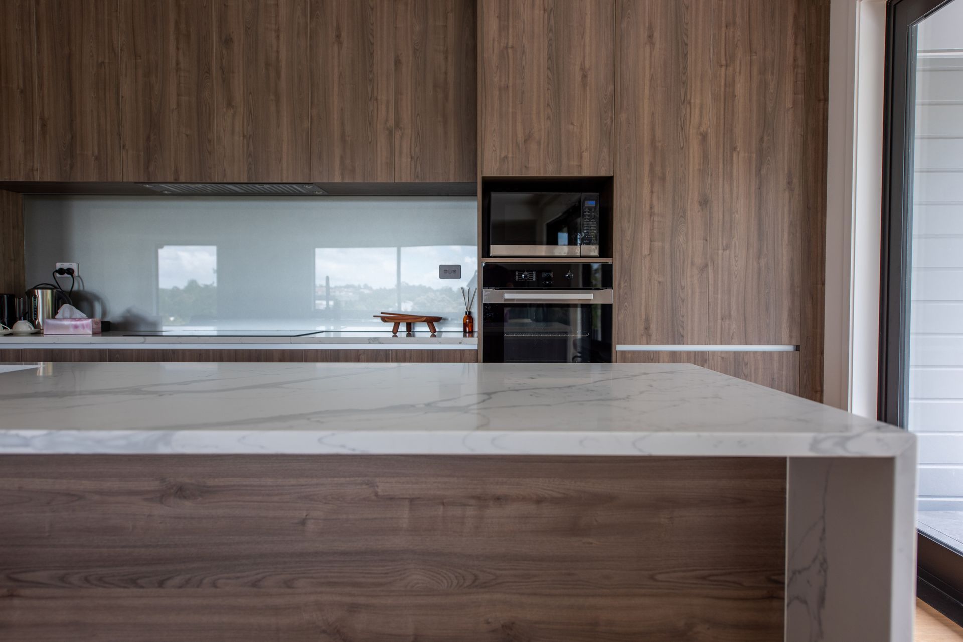 White kitchen with stainless steel appliances, a large island, and tile flooring.
